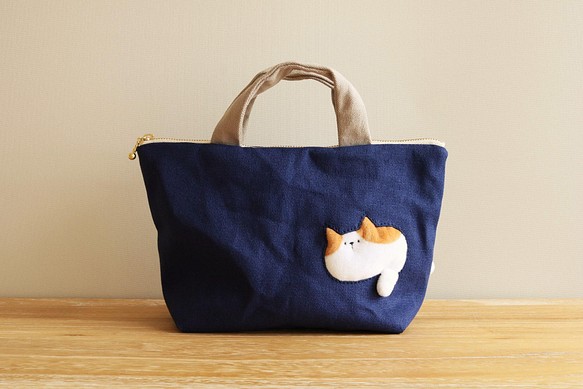 バッグを通り抜けようとする猫の小さめバッグ (茶×白猫 ネイビー系 ファスナー25cm ランチバッグ) 1枚目の画像