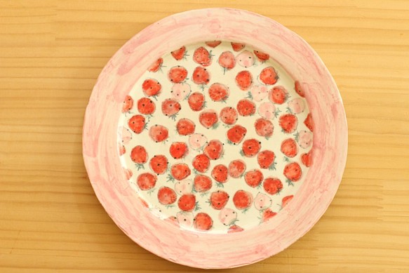 粉紅色和紅色的草莓菜在飲用粉色的外緣上。 第1張的照片