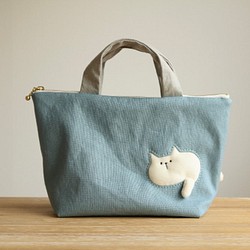 バッグを通り抜けようとする猫の小さめバッグ  (ぽっちゃり白猫 ブルー系 ファスナー25cm  持ち手グレー) 1枚目の画像