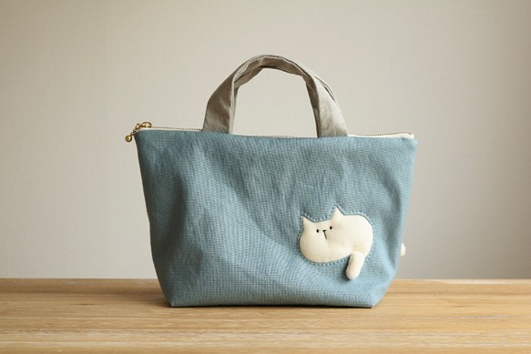 バッグを通り抜けようとする猫の小さめバッグ  (ぽっちゃり白猫 ブルー系 ファスナー25cm  持ち手グレー) 1枚目の画像
